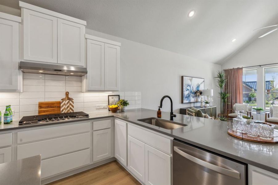 Kitchen featuring ventilation hood, white cabinetry, sink, and appliances with stainless steel finishes