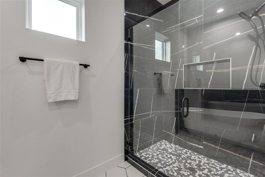 Primary bathroom shower enclosure with black natural stone.