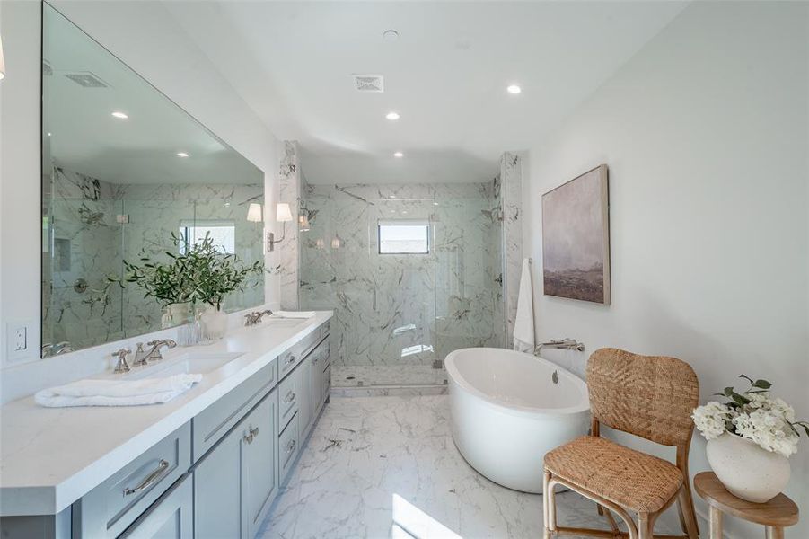 Primary bathroom featuring a wealth of natural light, double vanity, and independent shower and bath