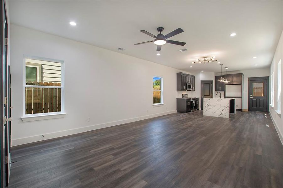 Unfurnished living room with dark hardwood / wood-style flooring, sink, and ceiling fan