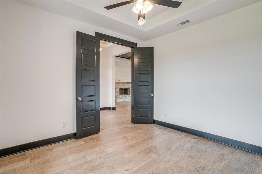 Unfurnished room with a tray ceiling, ceiling fan, and light wood-type flooring