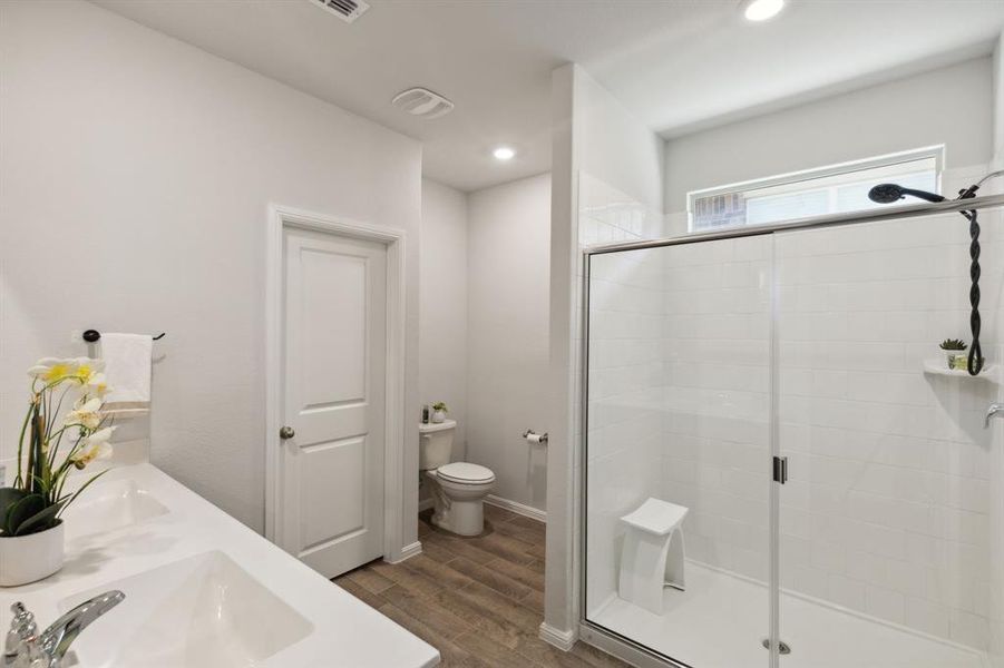 Bathroom featuring an oversized shower, hardwood / wood-style floors, toilet, and double sink