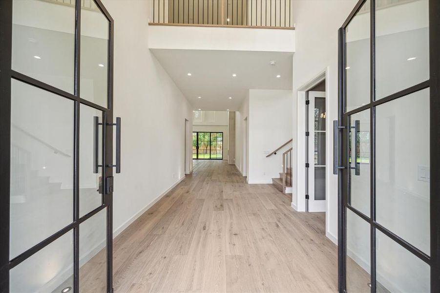 Step inside to a grand foyer with soaring ceilings and modern hardwood floors that flow throughout the home. Large windows in the open-concept layout offer abundant natural light, creating a warm and inviting atmosphere.