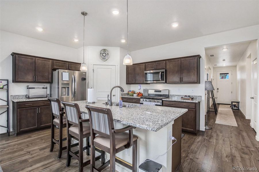 The kitchen features granite countertops, stainless steel appliances, large pantry and beautiful brown cabinets that match the flooring perfectly!