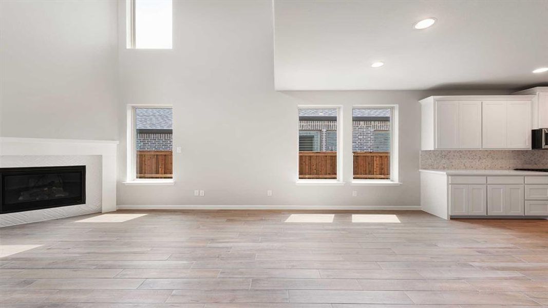 Unfurnished living room featuring a high ceiling, light wood-type flooring, and plenty of natural light