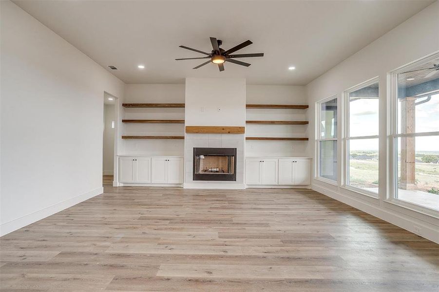 Unfurnished living room featuring light hardwood / wood-style flooring, ceiling fan, and a fireplace