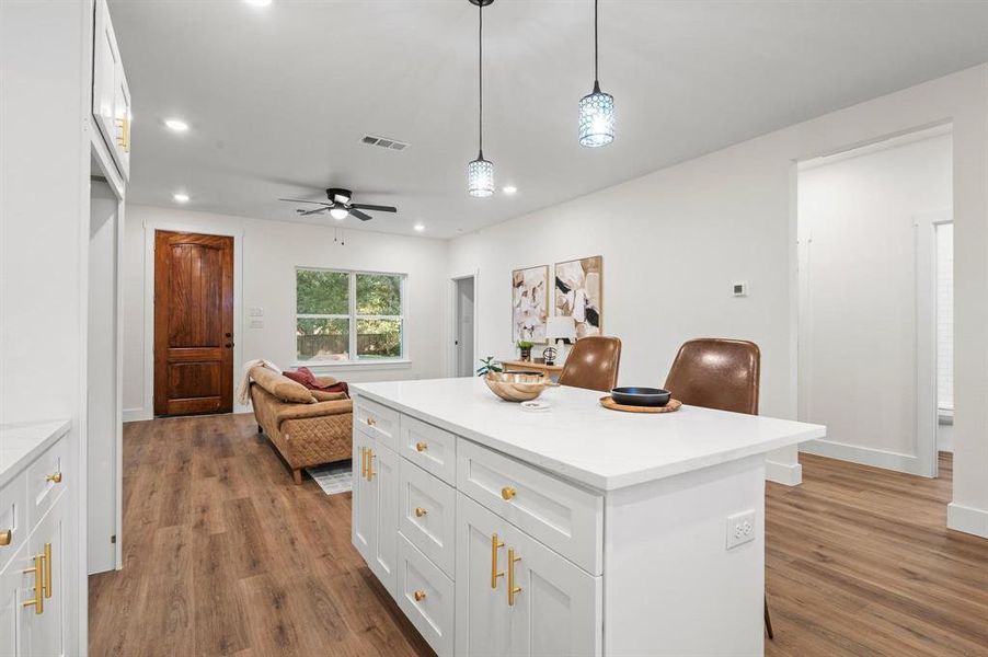 Kitchen with light hardwood / wood-style flooring, hanging light fixtures, a breakfast bar, white cabinetry, and ceiling fan