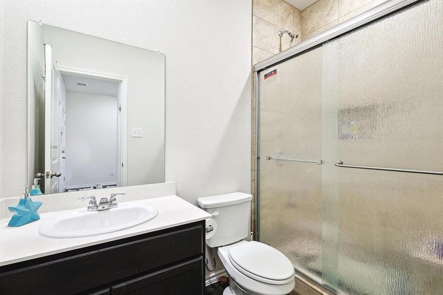 Bathroom with vanity, a shower with shower door, and toilet