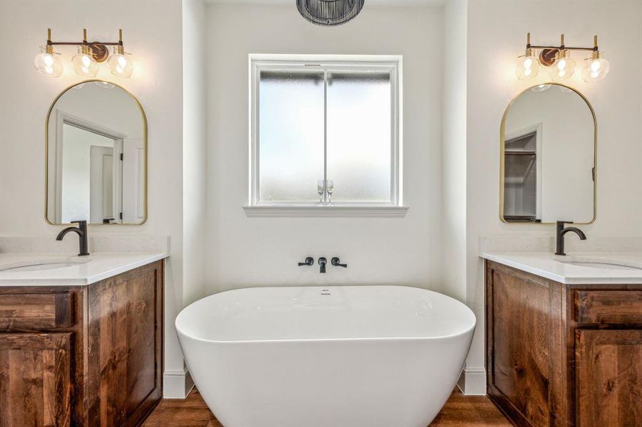 Bathroom with dual vanity, wood-type flooring, and a bathtub