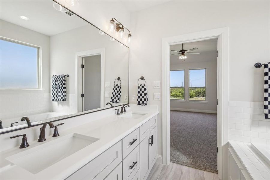 Bathroom with double vanity, ceiling fan, and a bathtub