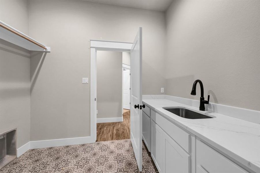 Laundry area featuring sink and light tile floors
