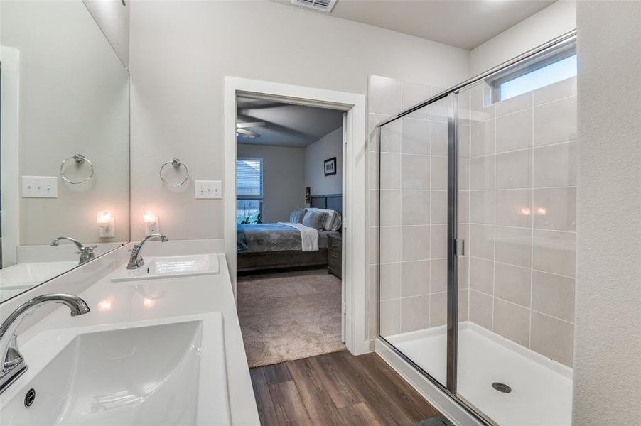 Bathroom with wood-type flooring, ceiling fan, an enclosed shower, and double vanity