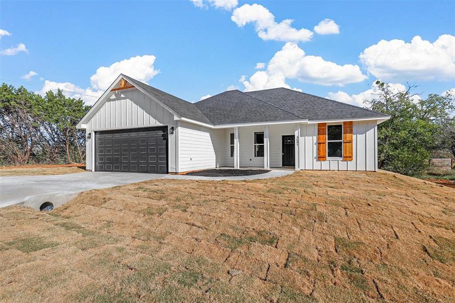 View of front of home with covered porch, a front lawn, and a garage