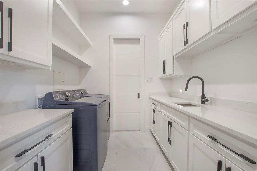 Laundry room with sink, washing machine and clothes dryer, and cabinets