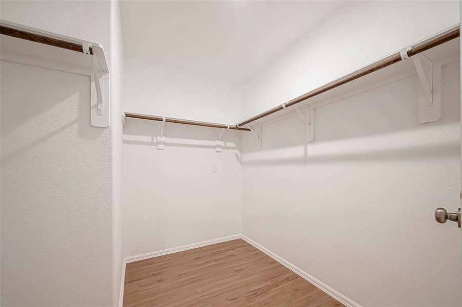 The primary closet is a spacious walk-in, offering multiple hanging bars and plenty of room for all your clothing.