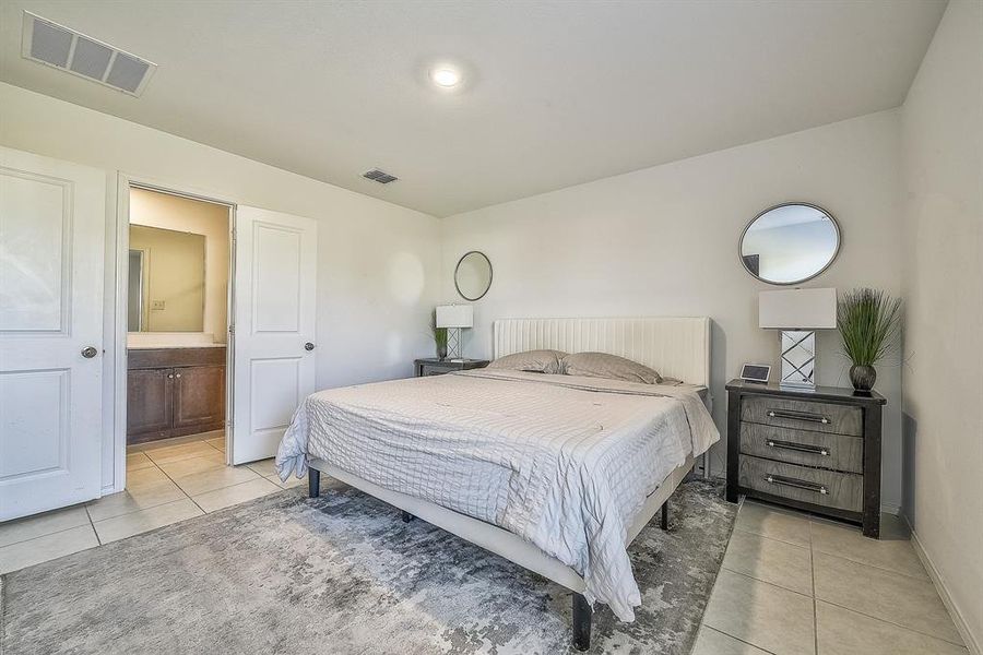 Bedroom with ensuite bathroom and light tile patterned floors