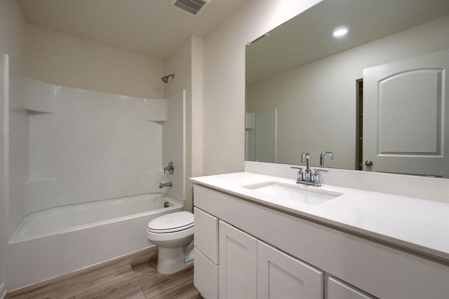 Full bathroom with toilet, shower / washtub combination, hardwood / wood-style flooring, and vanity