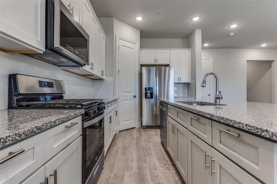 Kitchen with appliances with stainless steel finishes, sink, backsplash, and light hardwood / wood-style flooring