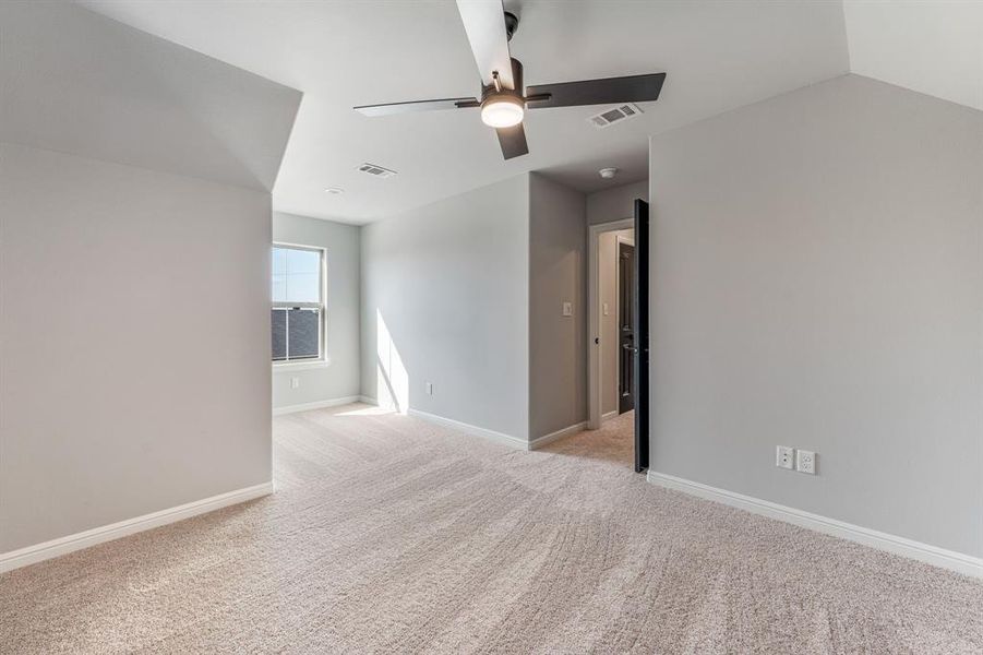 Empty room featuring lofted ceiling, light carpet, and ceiling fan