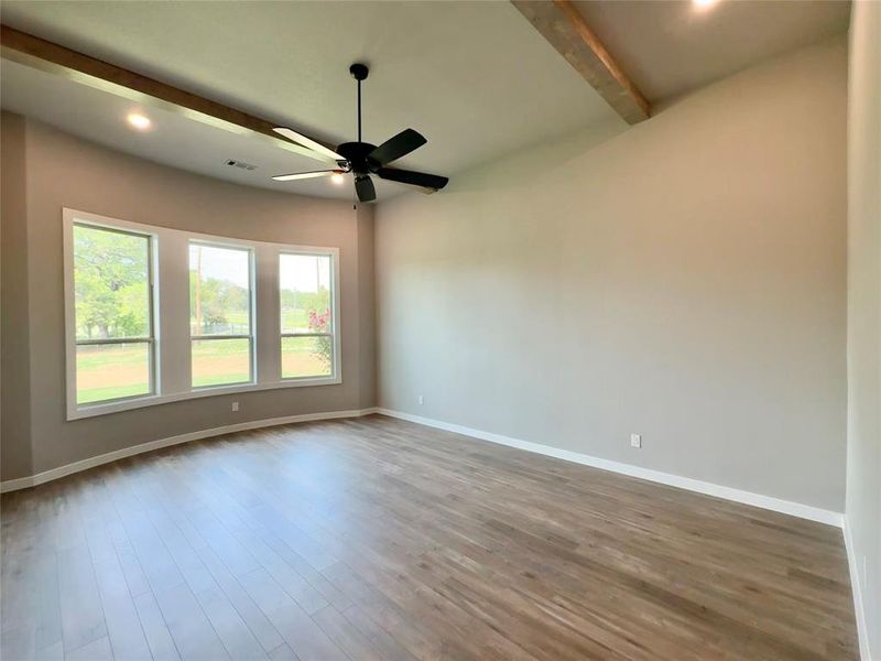 Primary room with light hardwood / wood-style flooring, ceiling fan, and beam ceiling