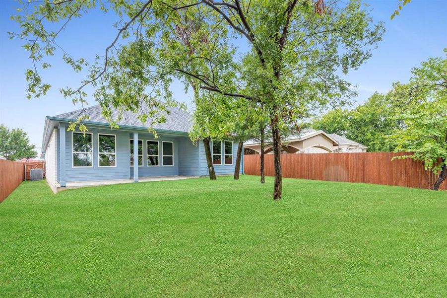 Rear view of property with a lawn and central AC