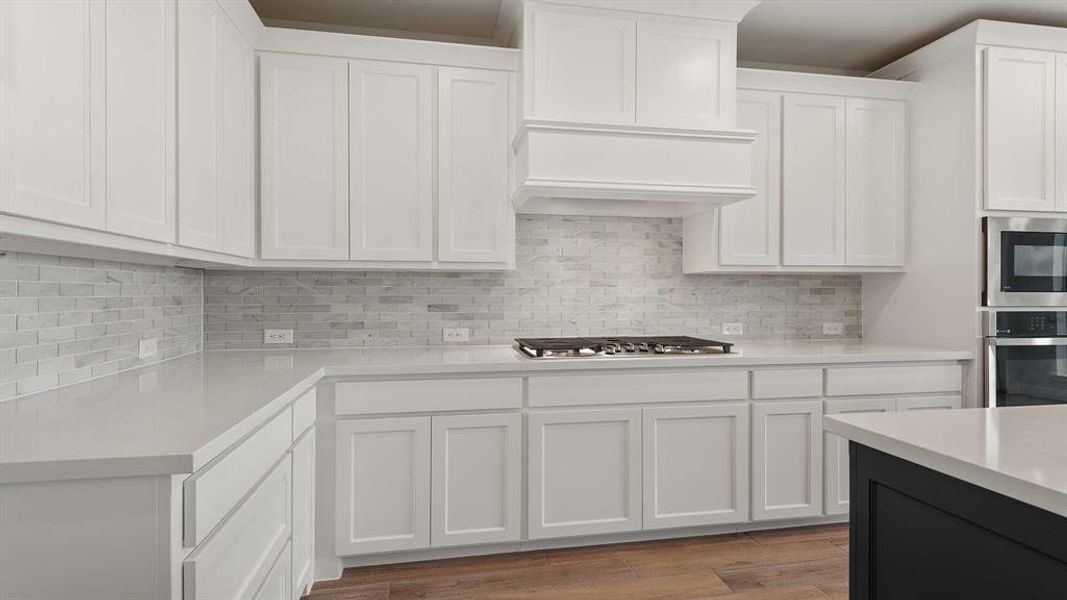 Kitchen featuring white cabinets, premium range hood, appliances with stainless steel finishes, and light hardwood / wood-style floors