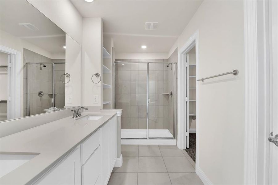 Bathroom featuring tile floors, dual vanity, and an enclosed shower
