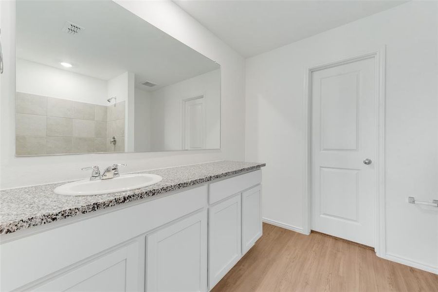 Bathroom featuring vanity, hardwood / wood-style floors, and a tile shower