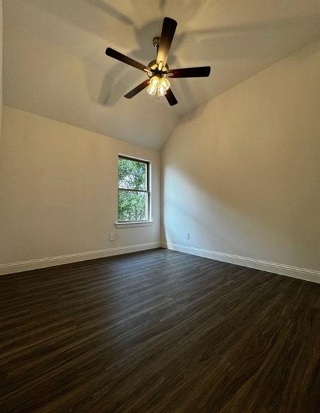 Unfurnished room with lofted ceiling, ceiling fan, and dark wood-type flooring