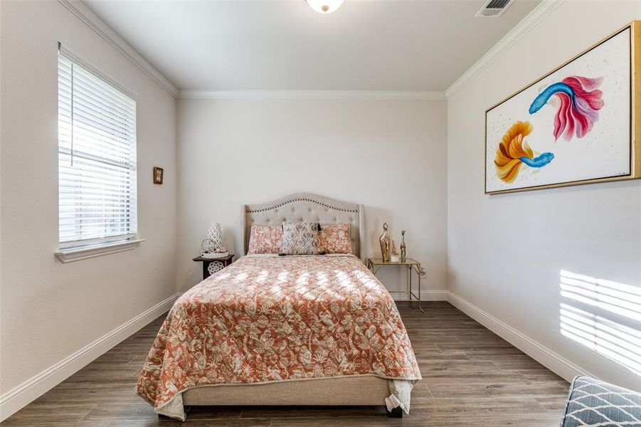 Bedroom with ornamental molding and hardwood / wood-style flooring