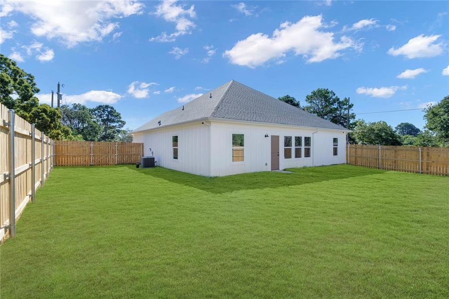 Back of property with a yard and central AC