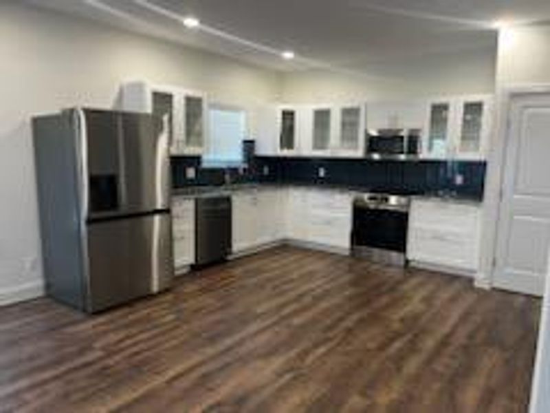 Kitchen featuring appliances with stainless steel finishes, dark hardwood / wood-style flooring, and white cabinets