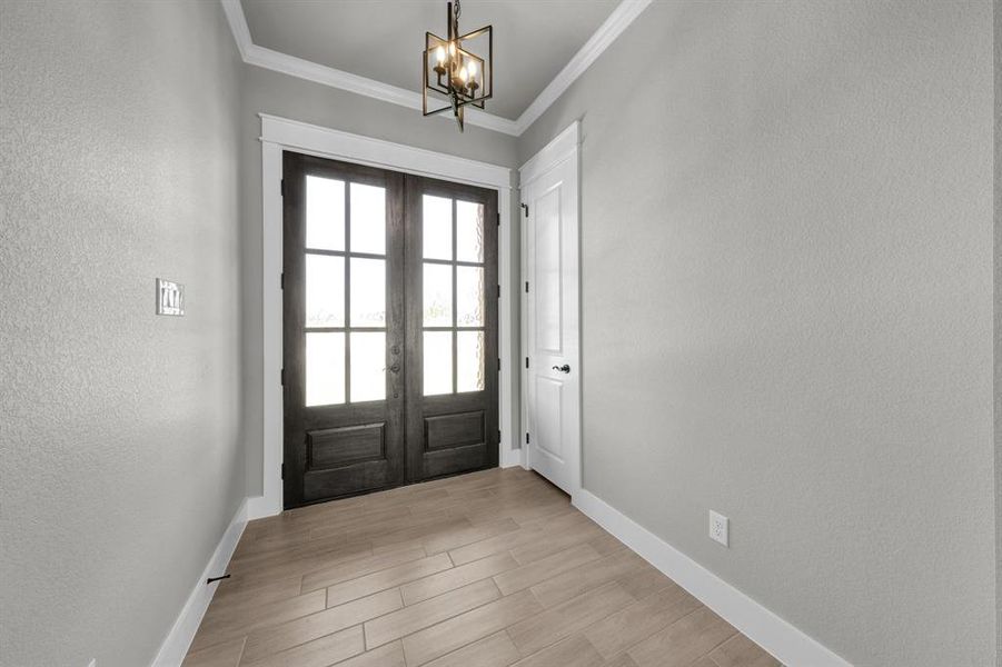 Doorway featuring a notable chandelier, french doors, and crown molding