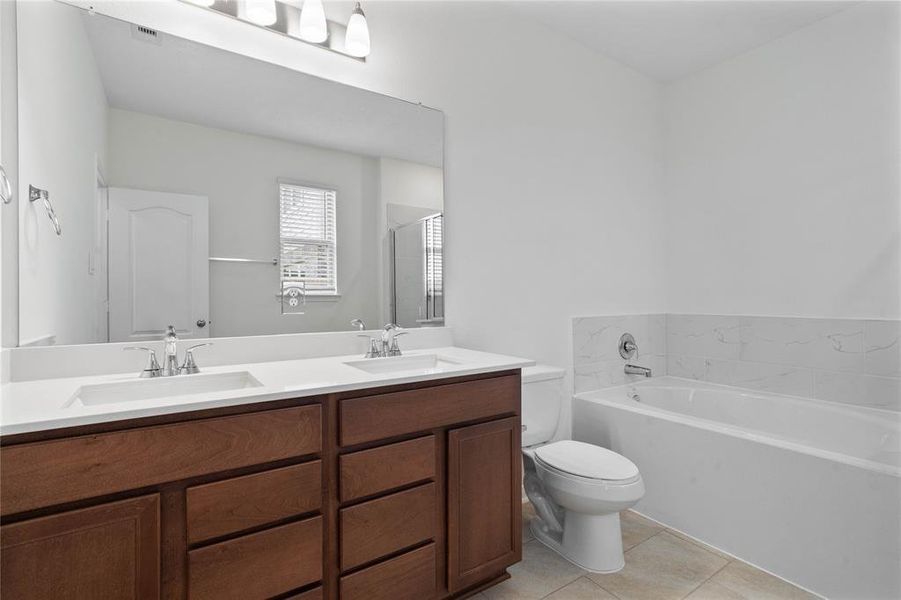 This primary bathroom is definitely move-in ready! Featuring a framed oversized walk-in shower with tile surround, stained cabinets with light countertops, spacious walk-in closet with shelving, high ceilings, custom paint, sleek and modern finishes.