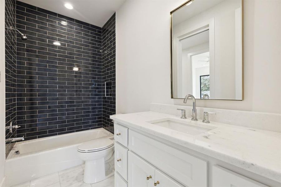 Full en suite bathroom featuring  glazed tiled shower / bath, vanity, and toilet