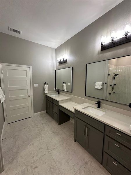 Bathroom featuring double sink vanity, tile flooring, and a shower