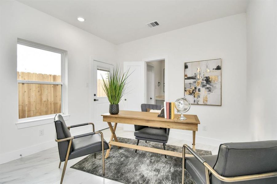 This first-floor bedroom, designed with ample storage, natural lighting, and flexible furniture arrangements, seamlessly transitions from a comfortable and functional office space to a cozy and inviting guest bedroom.