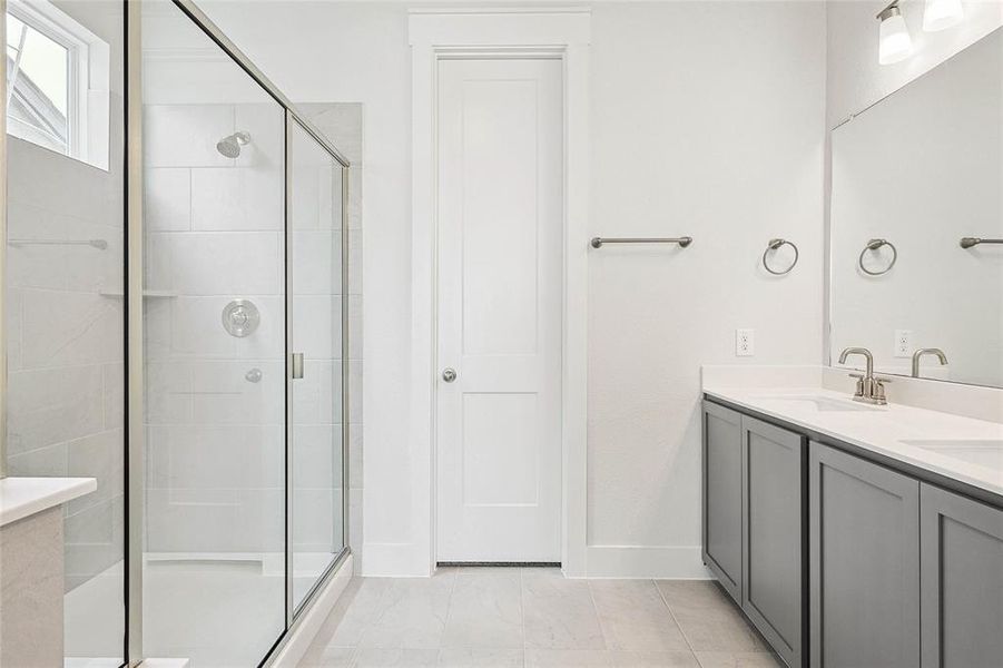 Bathroom featuring double vanity, a shower with door, and tile patterned floors