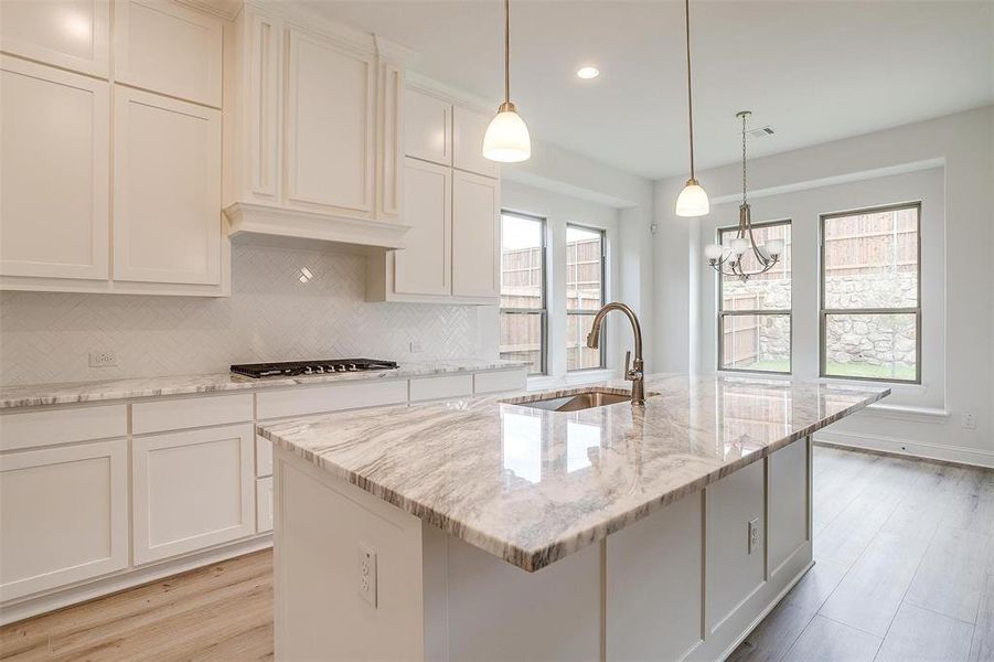 Kitchen featuring decorative backsplash, plenty of natural light, and a kitchen island with sink