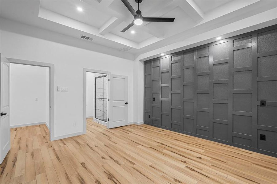 Empty room with coffered ceiling, ceiling fan, light hardwood / wood-style floors, and beamed ceiling