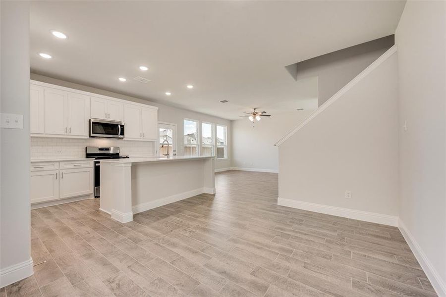 Kitchen with white cabinets, ceiling fan, appliances with stainless steel finishes, and light wood-type flooring