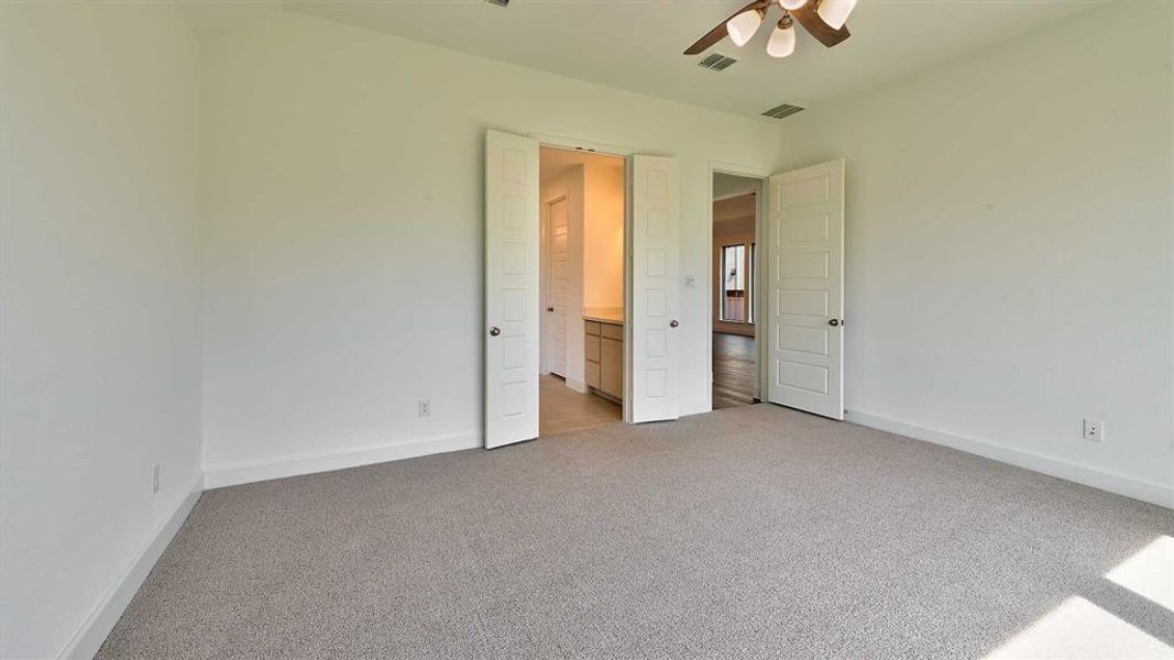 Unfurnished bedroom featuring carpet flooring, connected bathroom, and ceiling fan