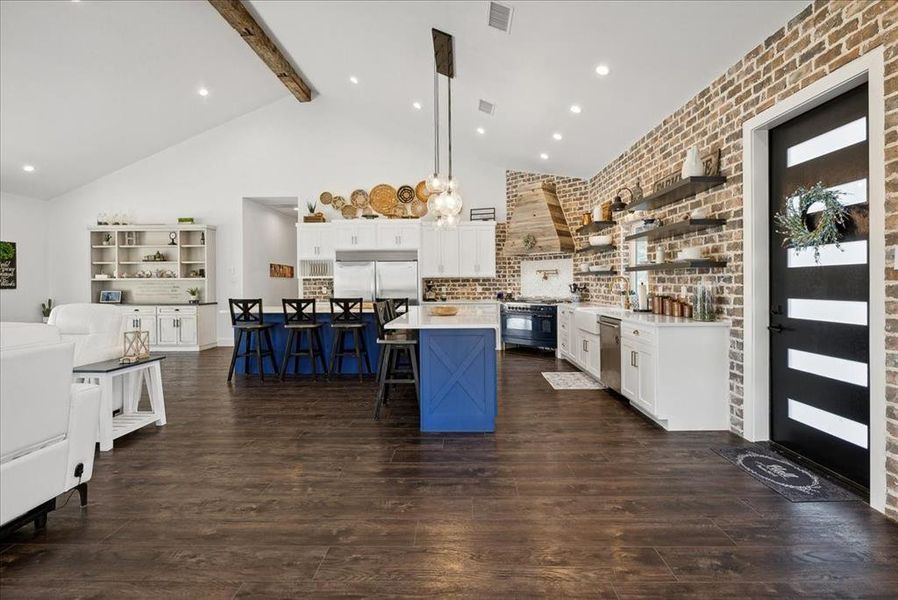 Kitchen featuring a center island, hanging light fixtures, dark wood-type flooring, a kitchen breakfast bar, and high quality appliances