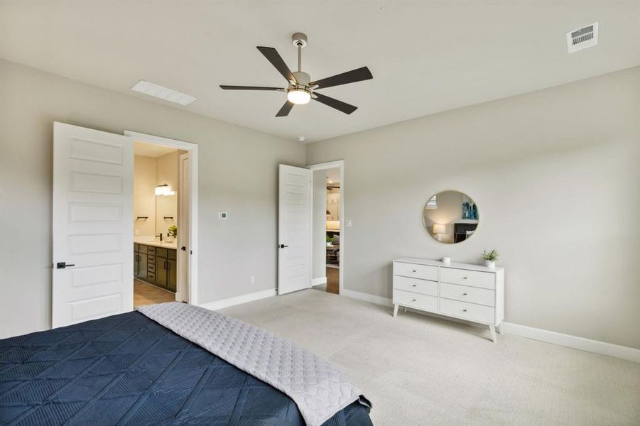 Bedroom featuring ceiling fan, light colored carpet, and connected bathroom