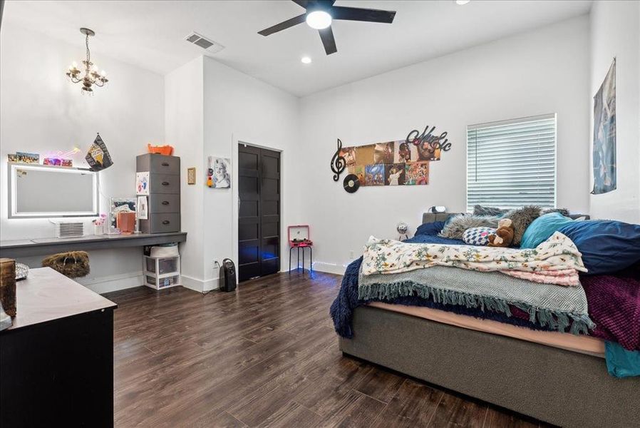 Bedroom featuring ceiling fan with notable chandelier and dark hardwood / wood-style floors