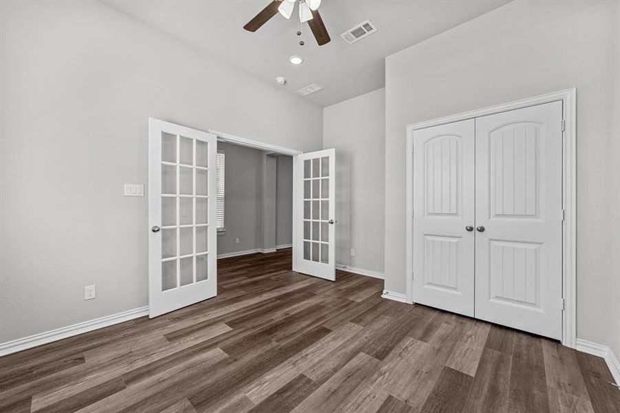 Unfurnished bedroom featuring french doors, dark hardwood / wood-style flooring, ceiling fan, and a closet