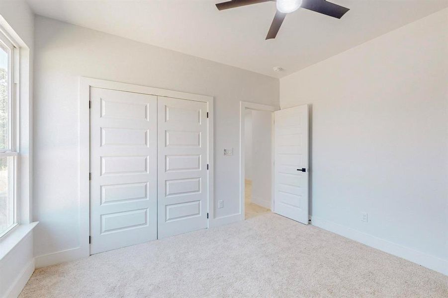 Unfurnished bedroom with light carpet, ceiling fan, and a closet