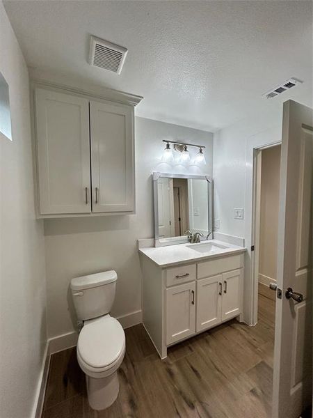 Bathroom featuring vanity, toilet, wood-type flooring, and a textured ceiling