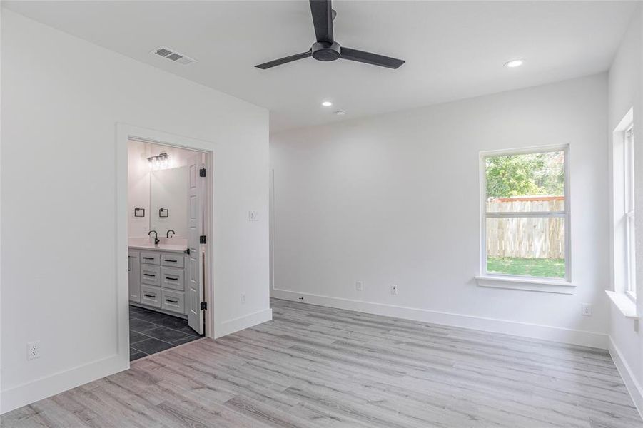 Unfurnished bedroom featuring sink, connected bathroom, hardwood / wood-style flooring, and ceiling fan