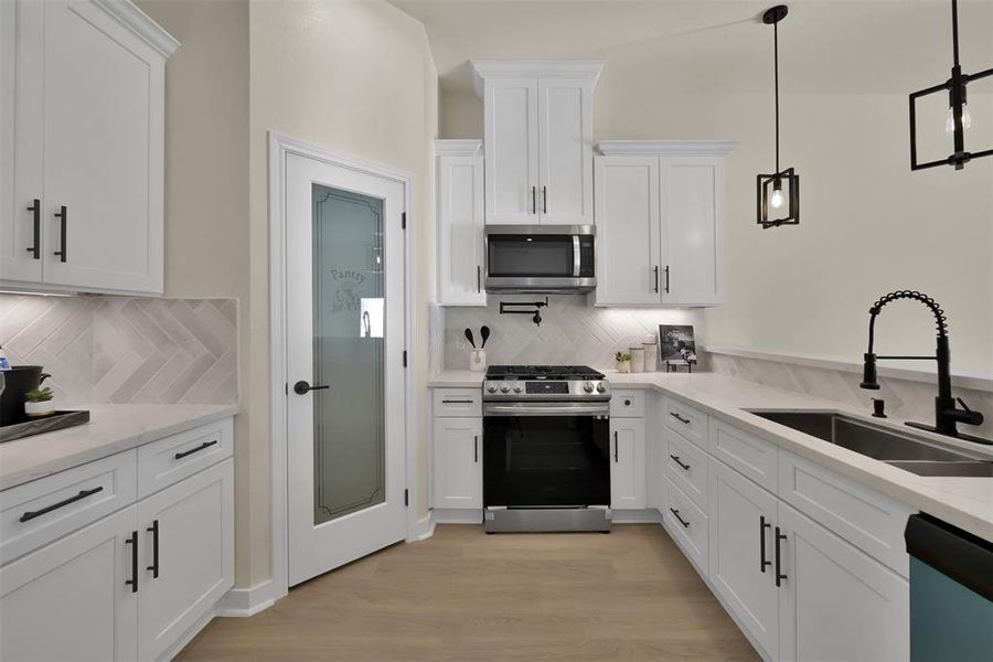 The kitchen features designer backsplash tile, quartz countertops, stainless appliances and a pot filler above the gas cooktop. A corner walk in pantry provides plenty of storage.